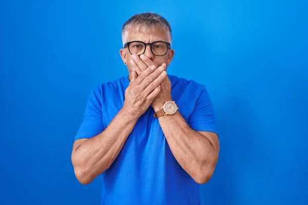 Hispanic Man Grey Hair Standing Blue Background Shocked Covering Mouth — Stock Photo, Image