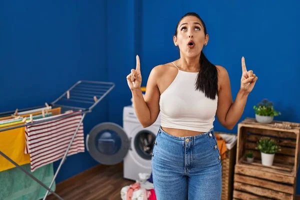 Ung Hispanic Kvinne Vaskerommet Forbløffet Overrasket Ser Opp Peker Med – stockfoto
