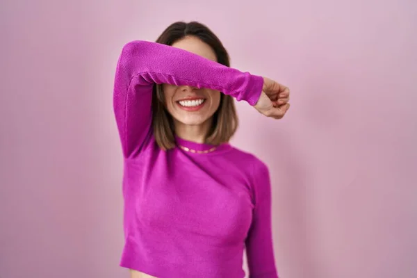 明るいと面白い笑みを浮かべて腕で目をカバーピンクの背景に立ってヒスパニック系の女性 視覚障害の概念 — ストック写真