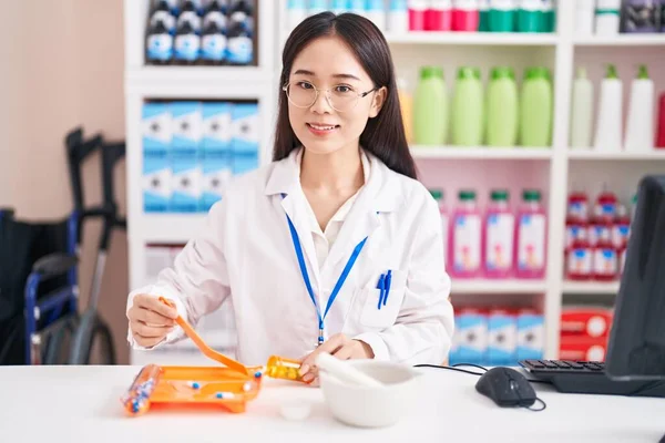 若い中国人女性薬剤師笑顔自信を持って組織薬用量で薬局 — ストック写真