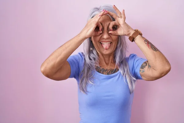 Μεσήλικη Γυναίκα Τατουάζ Που Στέκεται Πάνω Από Ροζ Φόντο Κάνει — Φωτογραφία Αρχείου