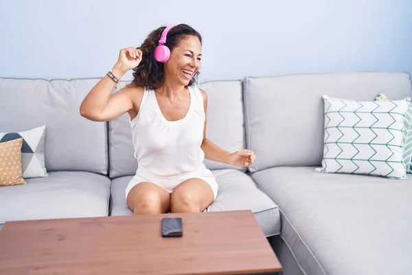 Middle age woman listening to music and dancing at home