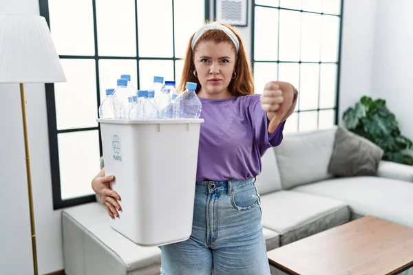 Young Redhead Woman Holding Recycling Wastebasket Plastic Bottles Looking Unhappy — Stock Photo, Image