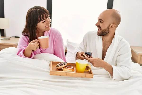 他的一对年轻夫妇坐在卧室的床上吃早餐 — 图库照片