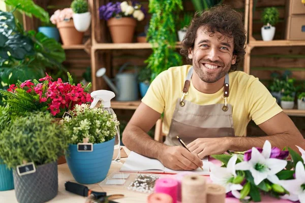 Junger Hispanischer Blumenhändler Lächelt Selbstbewusst Und Schreibt Auf Notizbuch Blumenladen — Stockfoto
