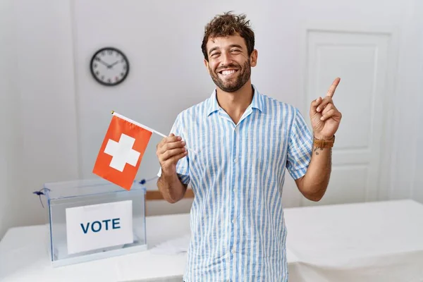 Молодой Красивый Мужчина Выборах Политическую Кампанию Держа Флаг Швейцарии Улыбаясь — стоковое фото
