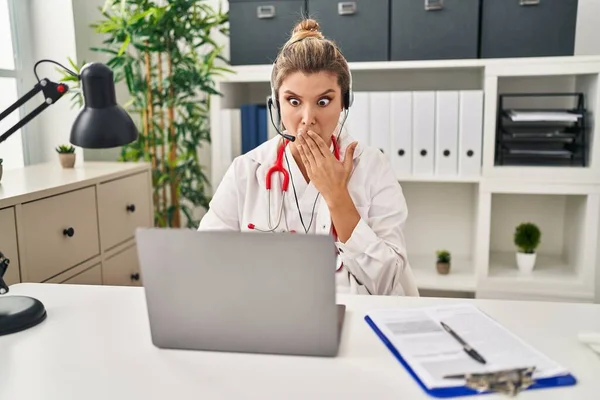 年轻的女医生穿着医生制服 手拿着电脑笔记本电脑捂着嘴工作 既震惊又害怕犯错 惊讶的表情 — 图库照片