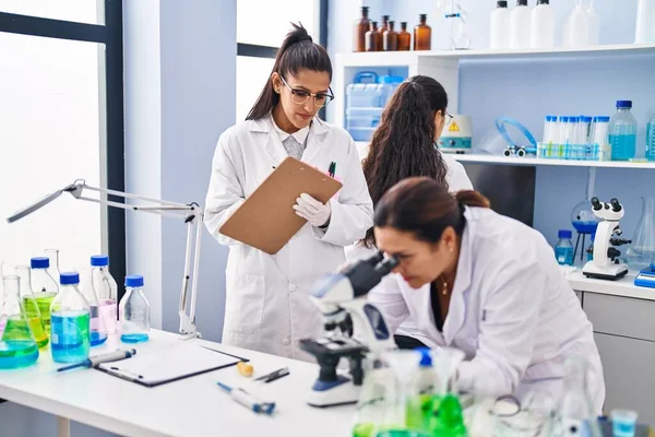 Три Жінки Вчені Які Використовують Мікроскоп Пишуть Контрольному Списку Лабораторії — стокове фото
