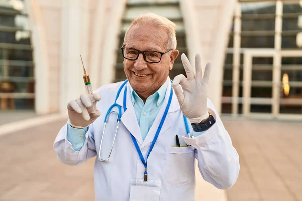 Старший Лікар Сірим Волоссям Тримає Шприц Роблячи Знак Пальцями Посміхаючись — стокове фото