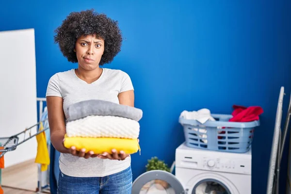 Black Woman Curly Hair Holding Clean Laundry Skeptic Nervous Frowning — ストック写真