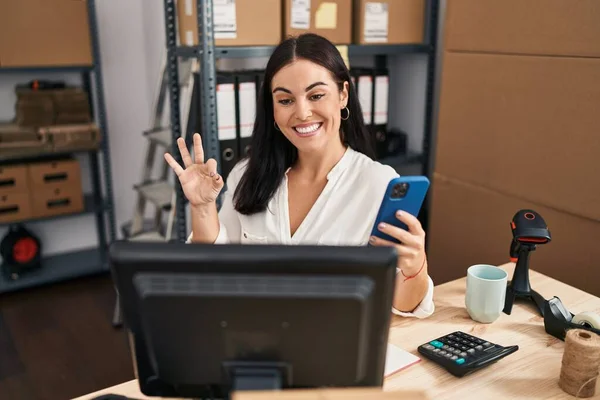 在小企业工作的年轻惊慌失措的女人 拿着智能手机 手拿着手签 微笑着表示友善的姿态 是个很好的象征 — 图库照片