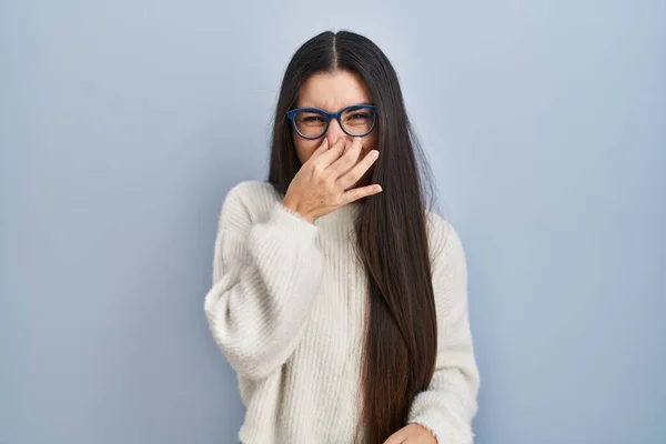 Young Hispanic Woman Wearing Casual Sweater Blue Background Smelling Something — ストック写真