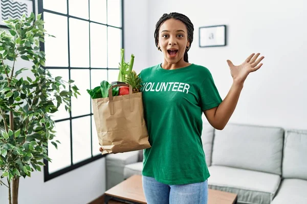 Young African American Woman Wearing Volunteer Shirt Holding Bag Groceries — ストック写真