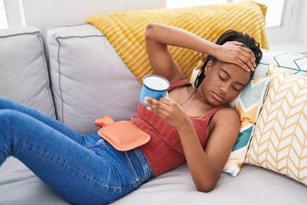非洲裔美国妇女躺在沙发上 家里有月经疼痛 — 图库照片