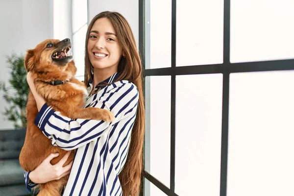 stock image Young hispanic woman smiling confident hugging dog standing at home