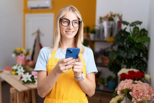 若いですブロンド女性花店でスマートフォンを使用して自信を持って笑顔 — ストック写真