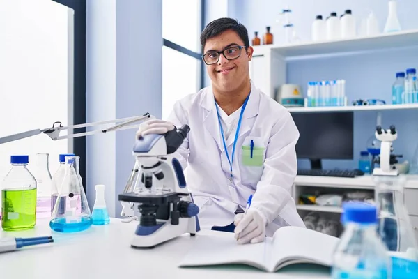 Homem Com Síndrome Vestindo Uniforme Cientista Usando Microscópio Escrevendo Caderno — Fotografia de Stock