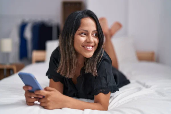 Young Hispanic Woman Using Smartphone Lying Bed Bedroom — Stock fotografie