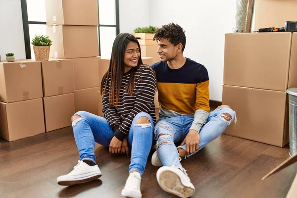 Young latin couple smiling happy sitting on the floor at new home.