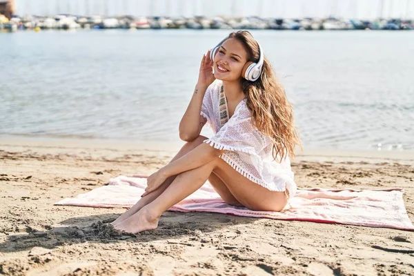 若い美しいですヒスパニック女性観光客に耳を傾け音楽に座って砂の上にビーチ — ストック写真