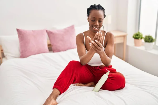 アフリカ系アメリカ人女性はベッドルームでベッドに座って皮膚治療を適用します — ストック写真