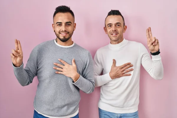 Homoseksualna Para Stojąca Różowym Tle Uśmiechnięta Przeklinająca Ręką Klatce Piersiowej — Zdjęcie stockowe