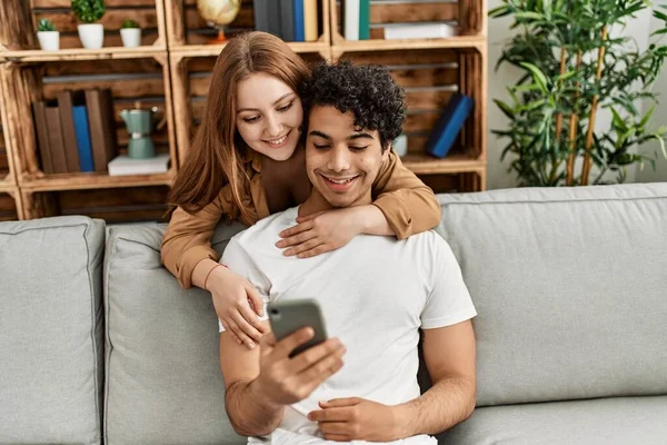 年轻夫妇快乐地微笑着 拥抱着坐在家里的沙发上 — 图库照片