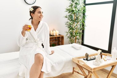 Genç İspanyol kadın kendine güvenen gülümsüyor Güzellik merkezinde şampanya içiyor.