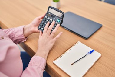 Young beautiful plus size woman using calculator at office