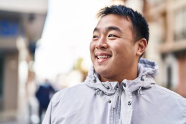 Young chinese man smiling confident standing at street