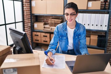 Genç ve güzel İspanyol kadın, iş kadını. Ofisteki evraklarda dizüstü bilgisayar kullanıyor.