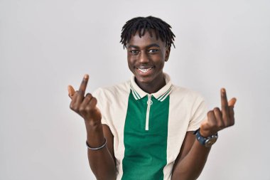 African man with dreadlocks standing over isolated background showing middle finger doing fuck you bad expression, provocation and rude attitude. screaming excited 