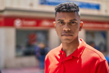 Young latin man with relaxed expression standing at street