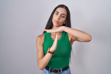 Tecrit edilmiş arka planda duran genç bir kadın. Elleriyle hareket ediyor, hayal kırıklığına uğramış ve ciddi bir yüz ifadesi takınıyor. 