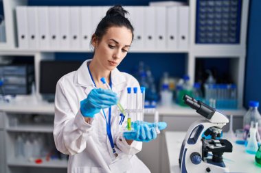 Young caucasian woman scientist holding test tubes at laboratory