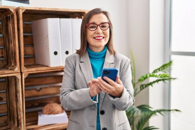 Orta yaşlı kadın psikolog psikoloji merkezinde akıllı telefon kullanıyor.