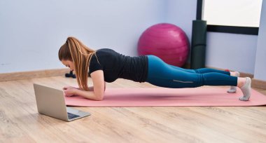 Young blonde woman having online training class at sport center