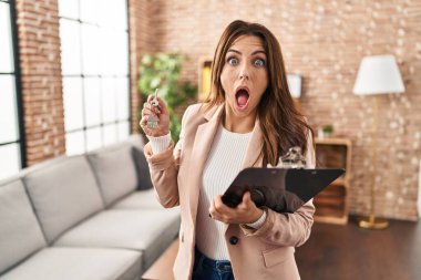 Yeni evin anahtarlarını elinde tutan esmer genç kadın şaşkınlık ve şaşkınlık ifadesi, korku ve heyecan dolu yüz ifadesiyle şok olmuştu.. 