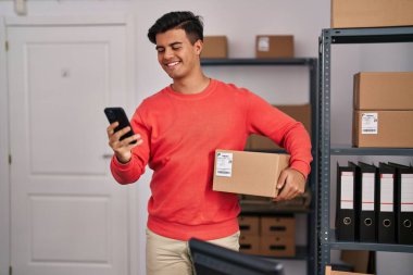 Genç bir İspanyol iş adamı ofiste akıllı telefon paketi kullanıyor.