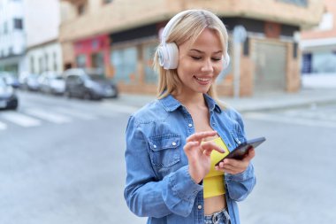 Sokakta müzik dinleyen kendine güvenen genç sarışın kadın.