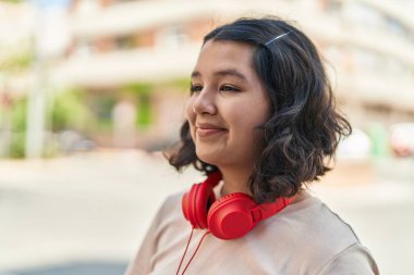 Sokakta kulaklık takan kendine güvenen genç bir kadın.