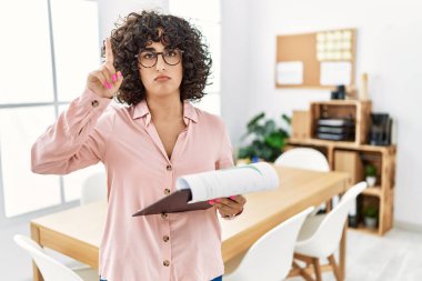 Ofiste iş elbisesi giyen genç ortadoğulu kadın üzgün ve üzgün görünüyor, parmaklarıyla yönü gösteriyor, mutsuz ve depresif.. 