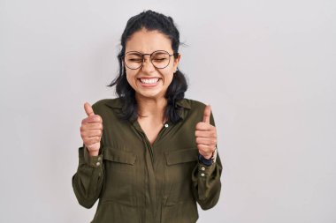 Koyu renk saçlı İspanyol kadın izole edilmiş arka planda duruyor. Kolları havada ve gözleri kapalı zaferi kutluyor. Kazanan konsept. 