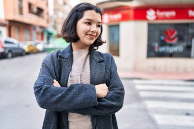 Young woman standing with arms crossed gesture looking to the side at street