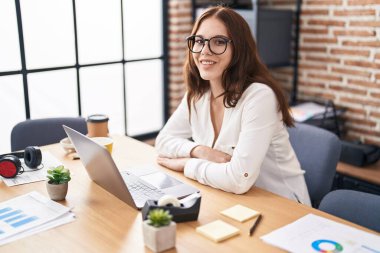 Ofiste çalışan genç bir iş kadını dizüstü bilgisayar kullanıyor.