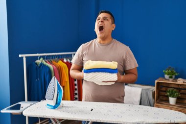 İspanyol genç adam ütüledikten sonra çamaşırları katladı kızgın ve öfkeli çığlıklar attı, öfkeyle bağırdı.. 