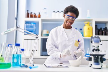 Laboratuvarda çalışan, bilim adamı üniforması giyen Afrikalı Amerikalı kadın.