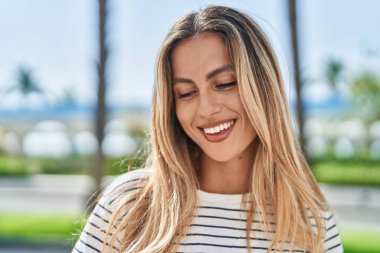 Young blonde woman smiling confident looking to the side at park