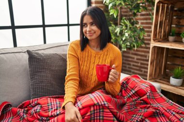 Genç İspanyol kadın kanepede oturuyor evde bir kahve içiyor gülümsüyor yan bakıyor ve düşünüyor.. 