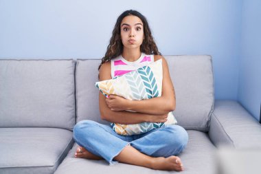 Genç İspanyol kadın kanepede oturmuş komik suratıyla yanaklarını şişiriyor. Ağzı havayla şişer, havayı yakalar.. 